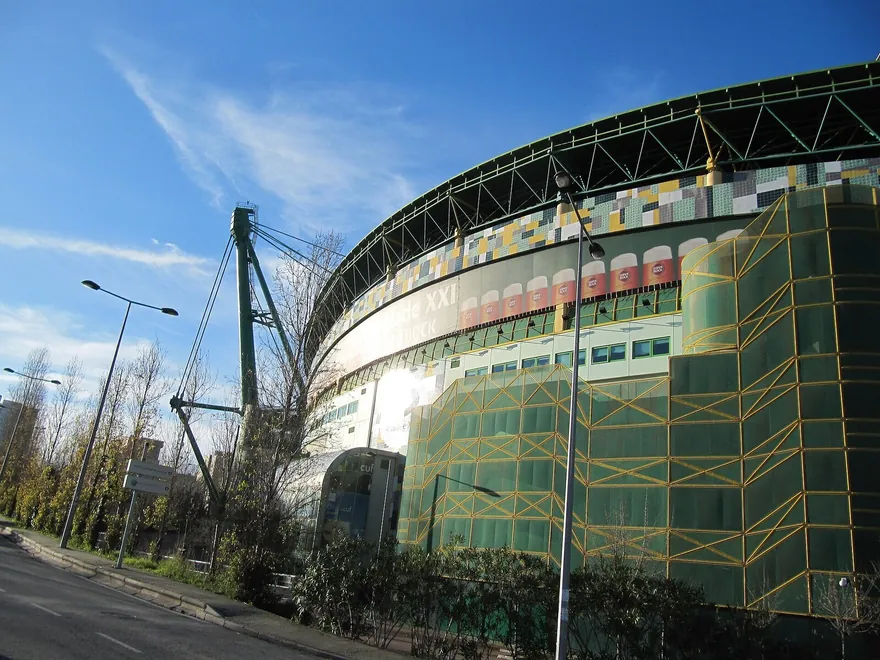Fachada exterior do Estádio José Alvalade com azulejos verdes e amarelos e a estrutura curva da cobertura